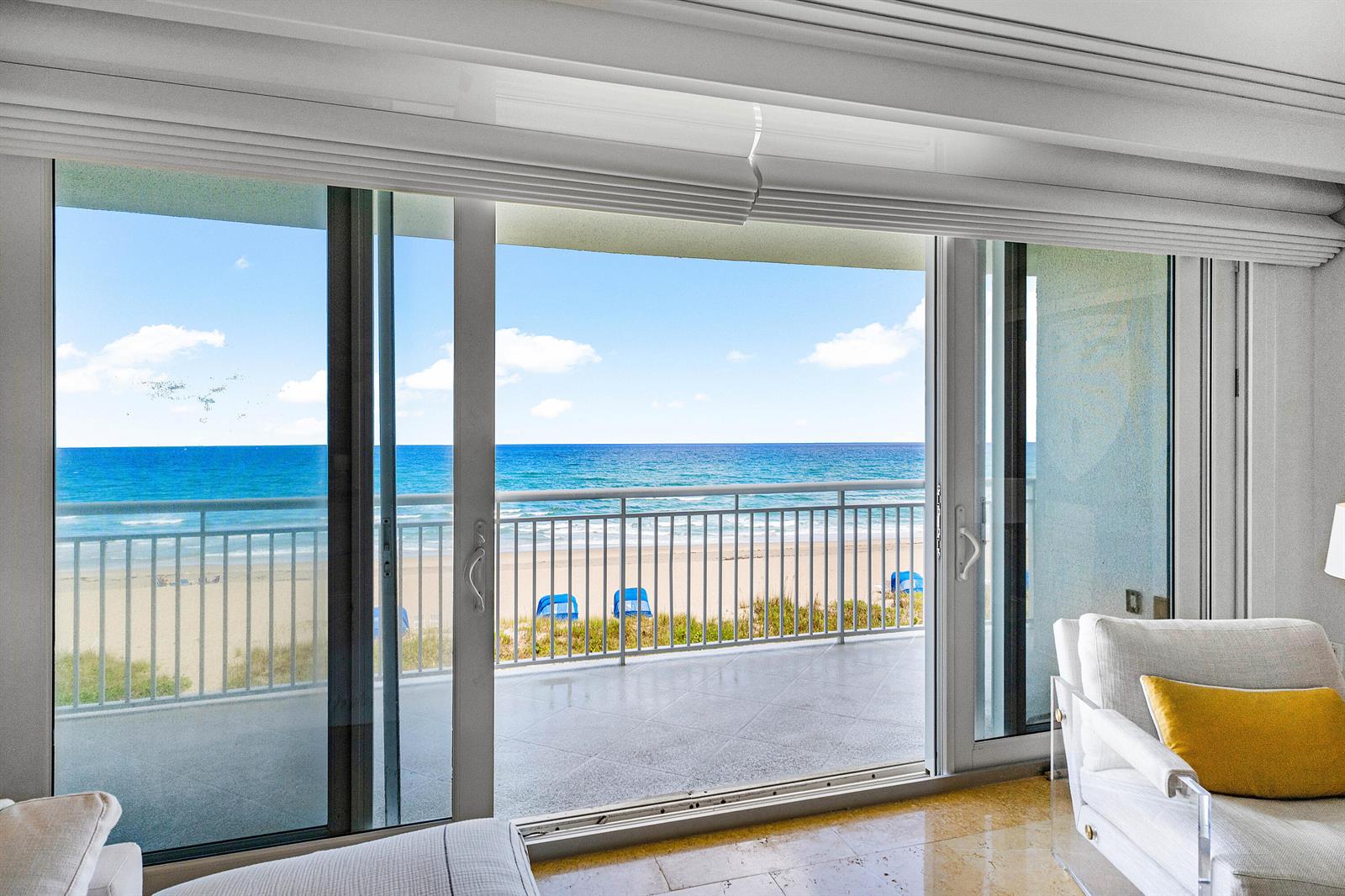A living room with sliding glass doors opening to a balcony overlooking the beach — 2780 S Ocean Boulevard # 401, Palm Beach FL 33480, PALM BEACH, FL