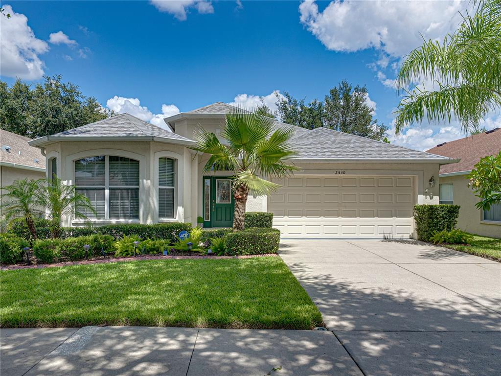 A single-story house with a beige stucco exterior, a two-car garage, and a palm tree — 2530 CROSS MORE STREET, VALRICO, FL