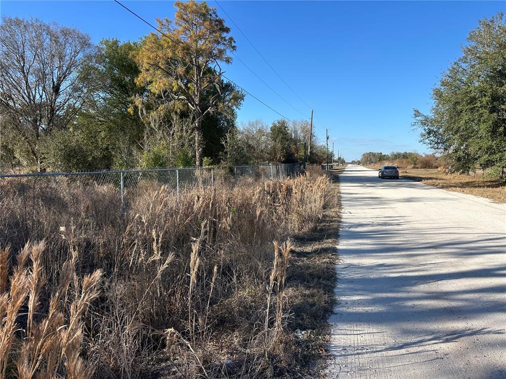 A gravel road runs alongside a chain-link fence bordering a field of tall, dry grass — 6000 US HIGHWAY 98 W, FROSTPROOF, FL