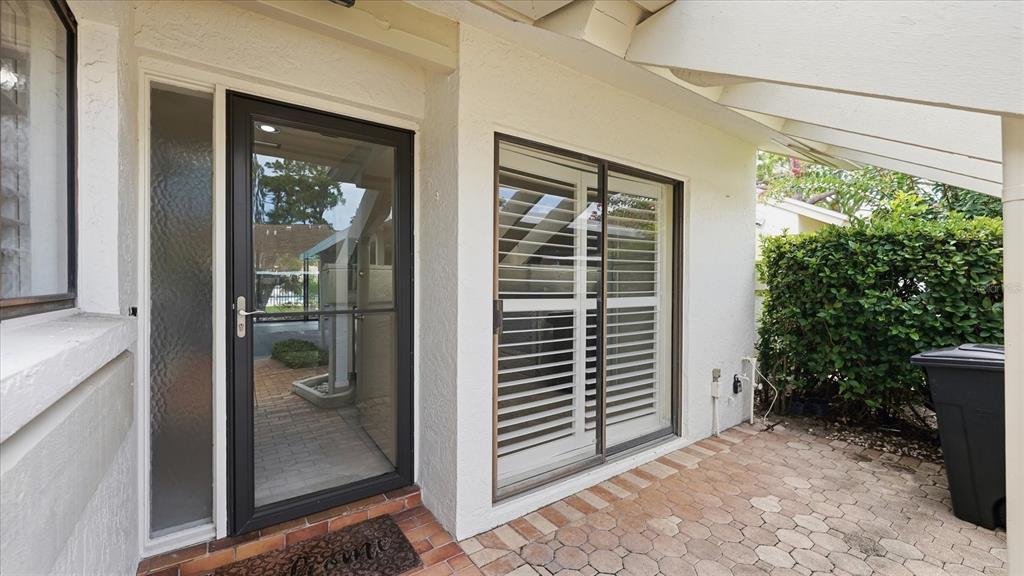 A paved patio features a glass storm door and a sliding glass door with shutters — 5350 MYRTLE UNIT 48, SARASOTA, FL