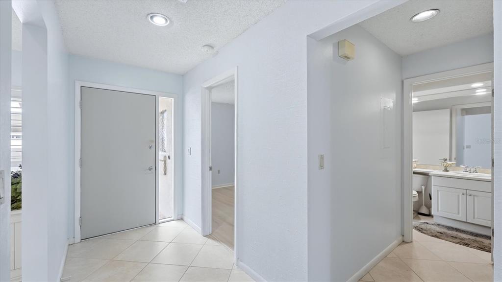 An entryway with light-colored tile flooring, a front door, and a view into a bathroom — 5350 MYRTLE UNIT 48, SARASOTA, FL
