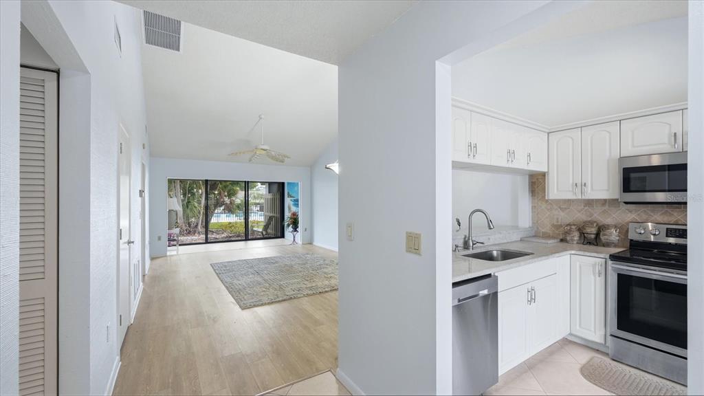 A kitchen with white cabinets and stainless steel appliances opens to a living area — 5350 MYRTLE UNIT 48, SARASOTA, FL