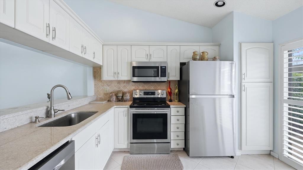A kitchen features white cabinets, stainless steel appliances, and light-colored granite countertops — 5350 MYRTLE UNIT 48, SARASOTA, FL