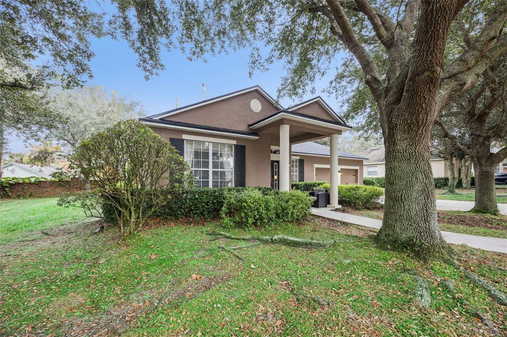 A single-story house with a covered entryway, columns, and large oak trees in the front yard — 629 MARY PAULA DRIVE, APOPKA, FL