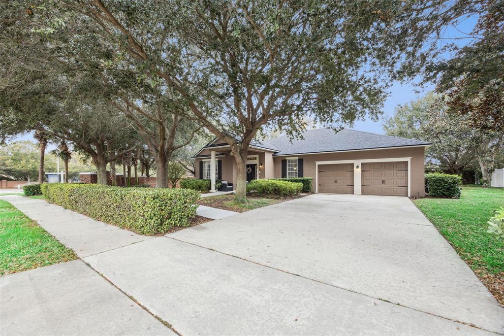 A single-story house with a two-car garage, concrete driveway, and large trees in the front — 629 MARY PAULA DRIVE, APOPKA, FL