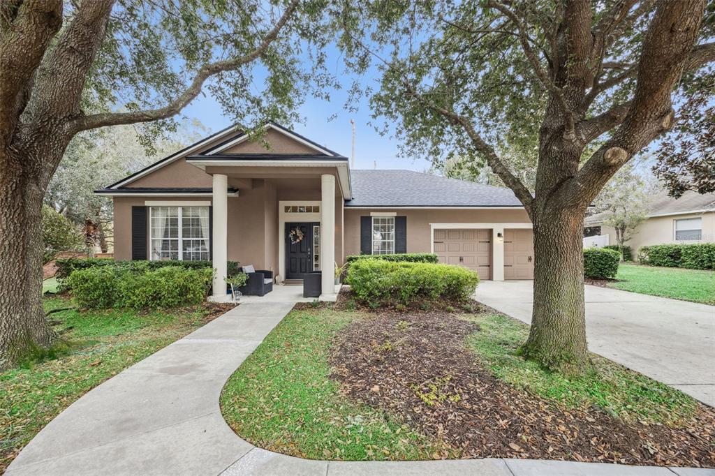 A single-story house with a brown exterior, two-car garage, and large oak trees in front — 629 MARY PAULA DRIVE, APOPKA, FL