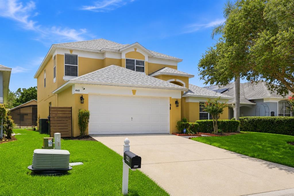A two-story yellow house with a white garage door and a concrete driveway — 440 LANGHAM DRIVE, DAVENPORT, FL