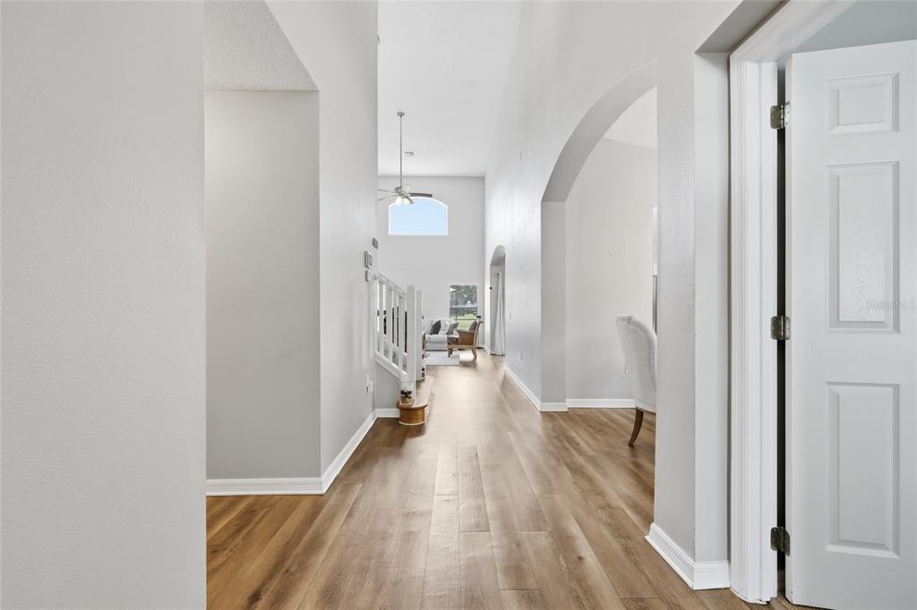 A hallway with light wood flooring leads toward a living area with high ceilings — 440 LANGHAM DRIVE, DAVENPORT, FL
