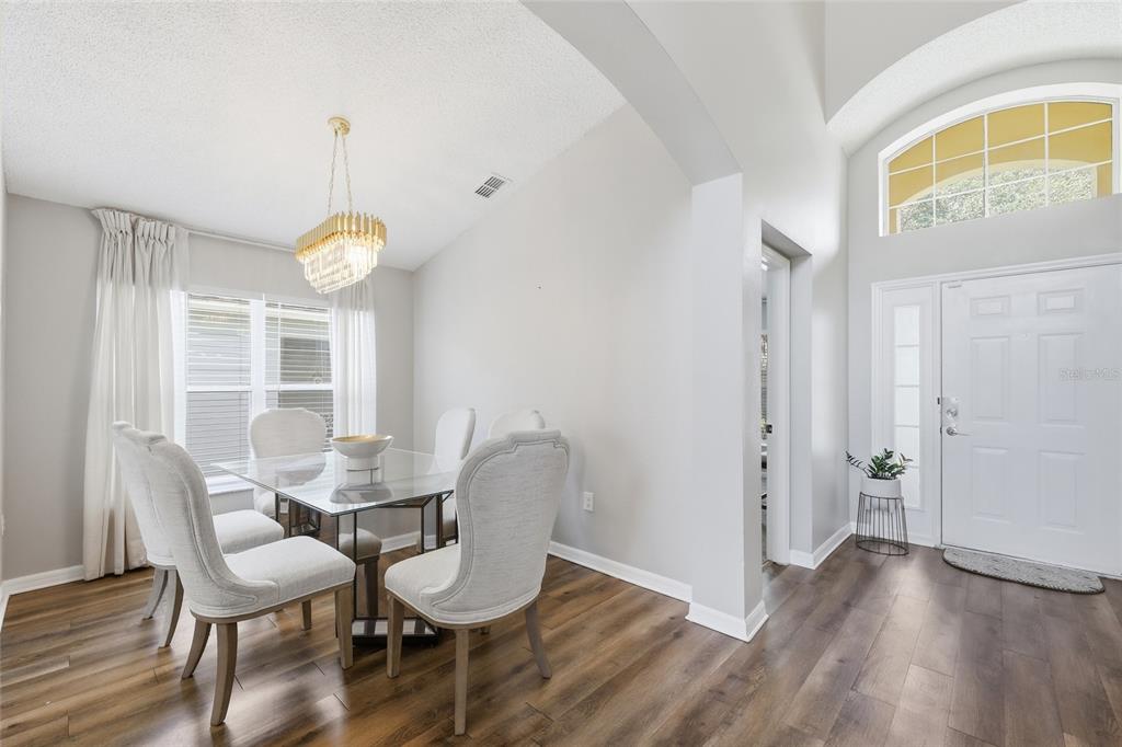 A dining area with a glass table and chairs sits beside an entryway with wood floors — 440 LANGHAM DRIVE, DAVENPORT, FL