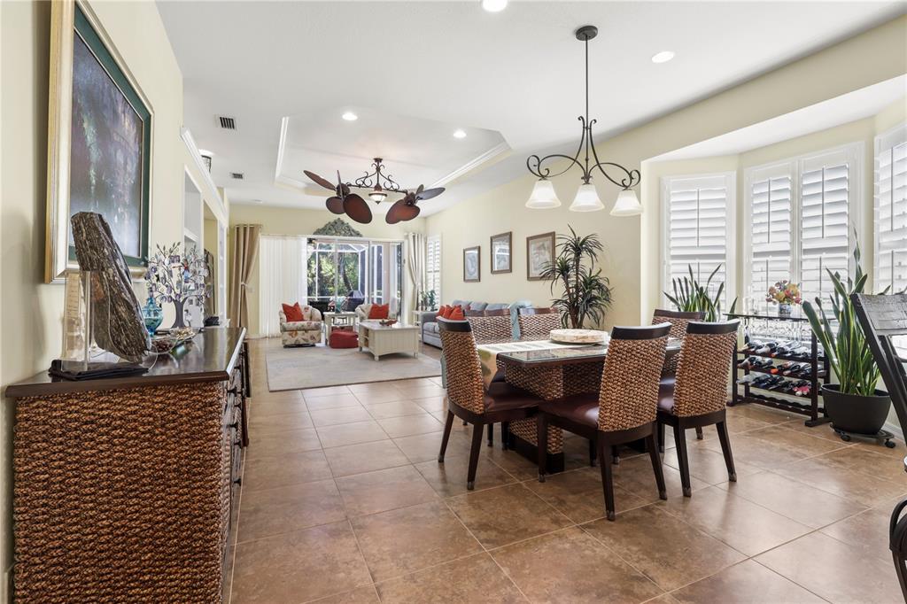 An open-concept dining and living area features tile flooring, a tray ceiling, and large windows — 1848 LANCASHIRE DRIVE UNIT 1848, VENICE, FL