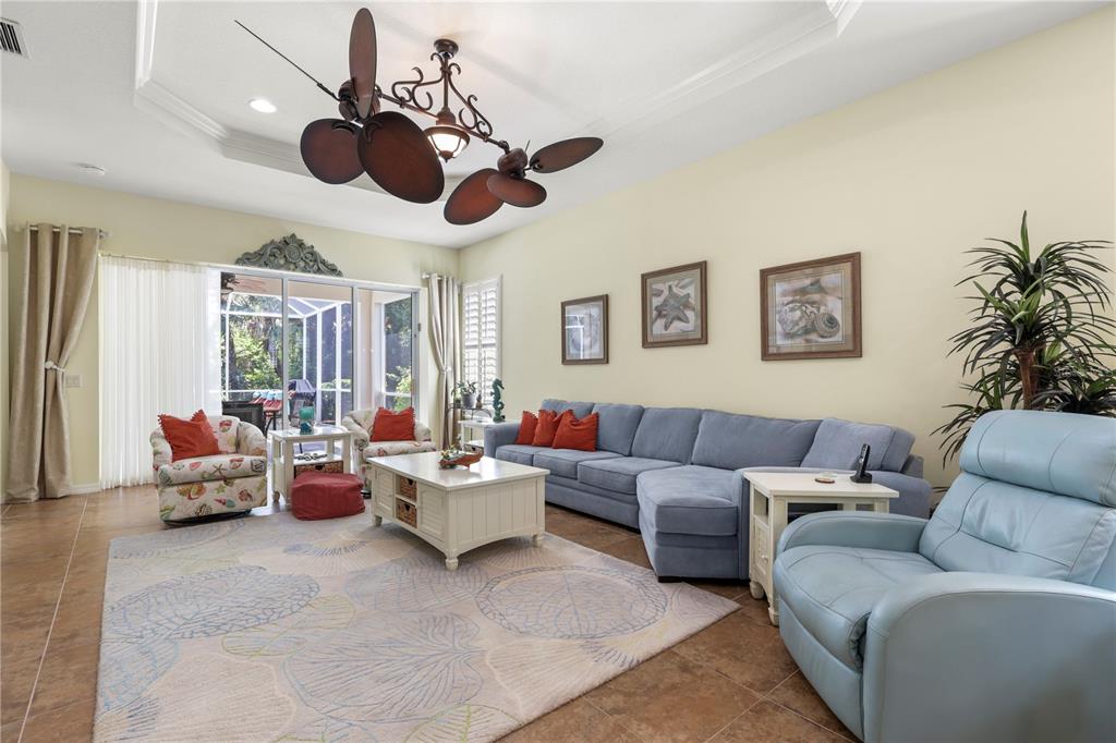 A living room features a blue sectional sofa, a patterned rug, and a ceiling fan — 1848 LANCASHIRE DRIVE UNIT 1848, VENICE, FL