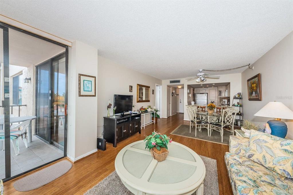 A living room with wood flooring, a round coffee table, and an adjacent dining area — 6218 PALMA DEL MAR BOULEVARD S UNIT 401, ST PETERSBURG, FL