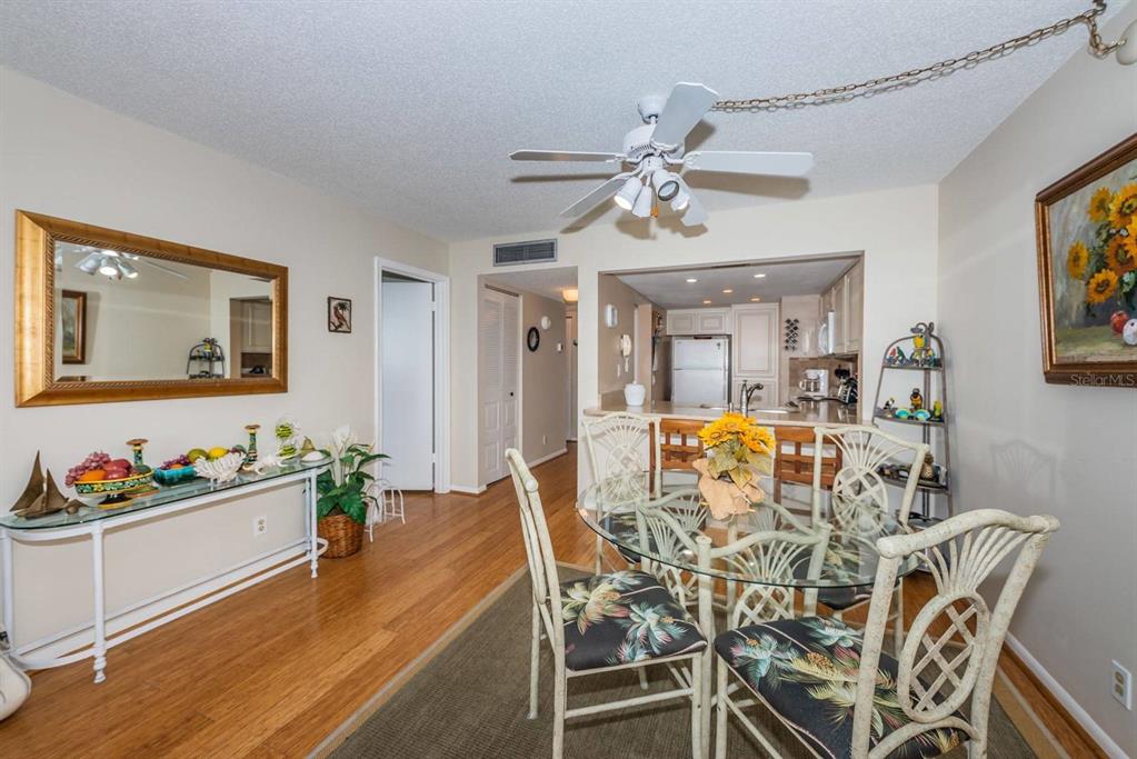 A dining area with a glass table, wicker chairs, and a console table on wood floors — 6218 PALMA DEL MAR BOULEVARD S UNIT 401, ST PETERSBURG, FL