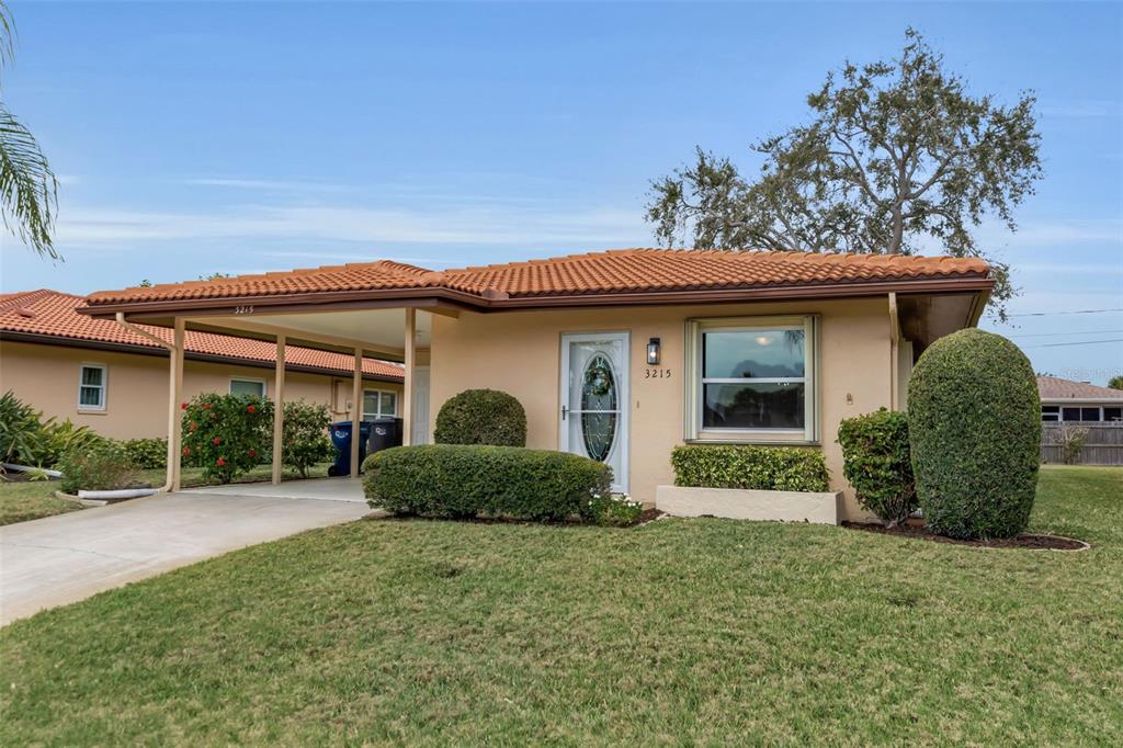 A single-story house with a tan exterior, orange tile roof, and an attached carport — 3215 MERCER ROAD, BRADENTON, FL
