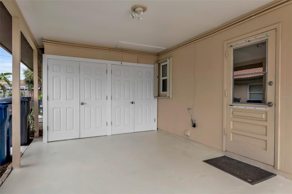A covered patio features white storage closet doors, a beige exterior wall, and a screen door — 3215 MERCER ROAD, BRADENTON, FL
