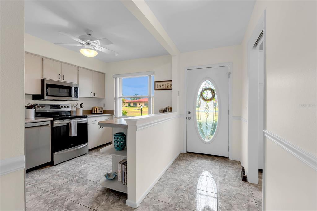 A kitchen with white cabinets, stainless steel appliances, and a tiled floor near an entryway — 3215 MERCER ROAD, BRADENTON, FL