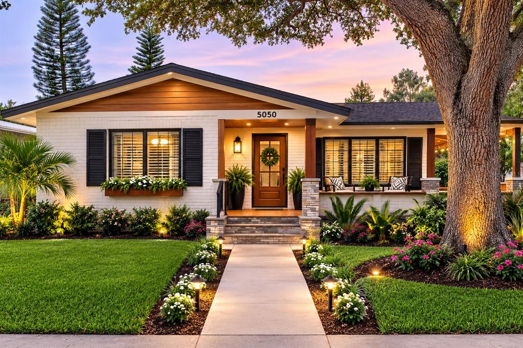 A single-story house with white brick, a wood-trimmed porch, and a landscaped front yard — 5050 29TH AVENUE N, ST PETERSBURG, FL