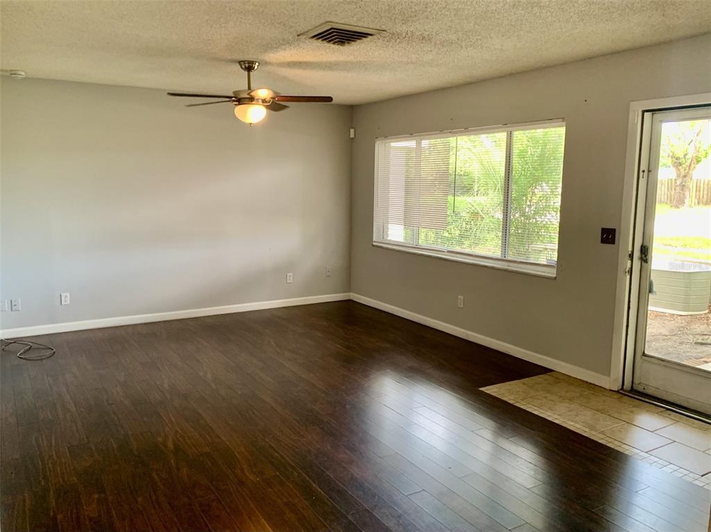 An empty living room features dark wood flooring, light gray walls, and a ceiling fan — 5050 29TH AVENUE N, ST PETERSBURG, FL