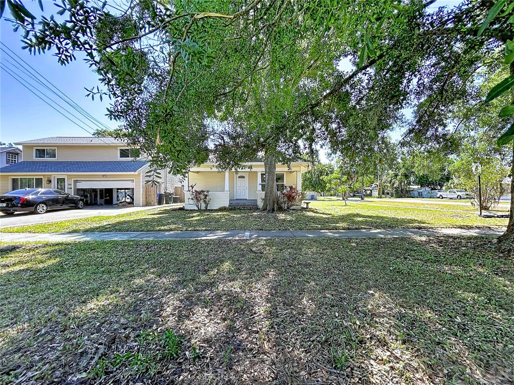 A light yellow house with a front porch sits behind a large tree and lawn — 313 JEFFERSON AVENUE S, OLDSMAR, FL