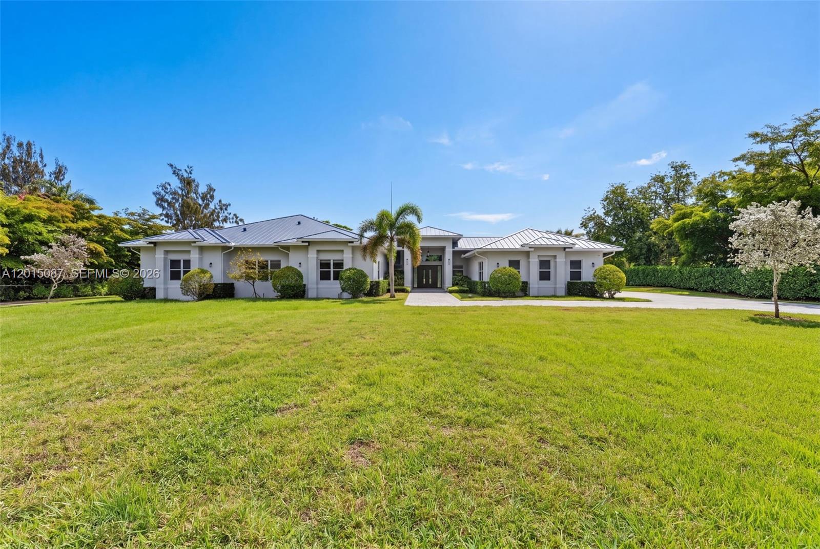 A single-story house with a metal roof and a large front lawn under a blue sky — 2400 SW 112th Ave, Davie FL 33325, DAVIE, FL