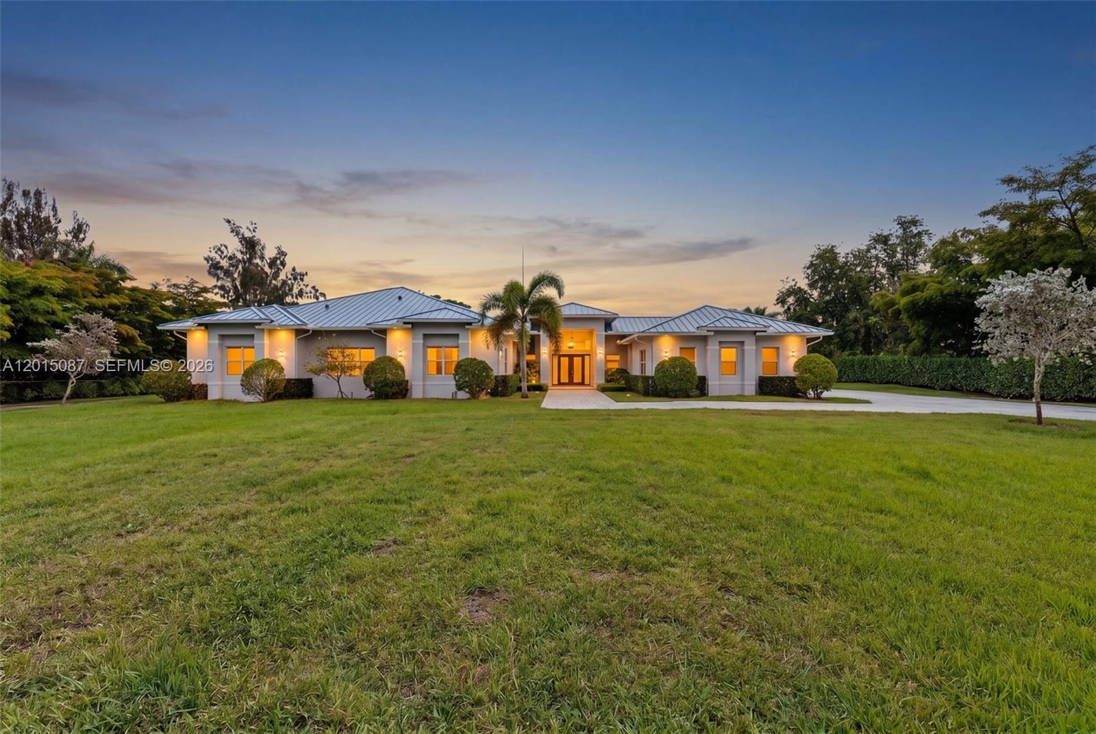 A single-story house with a metal roof and a large front lawn at dusk — 2400 SW 112th Ave, Davie FL 33325, DAVIE, FL