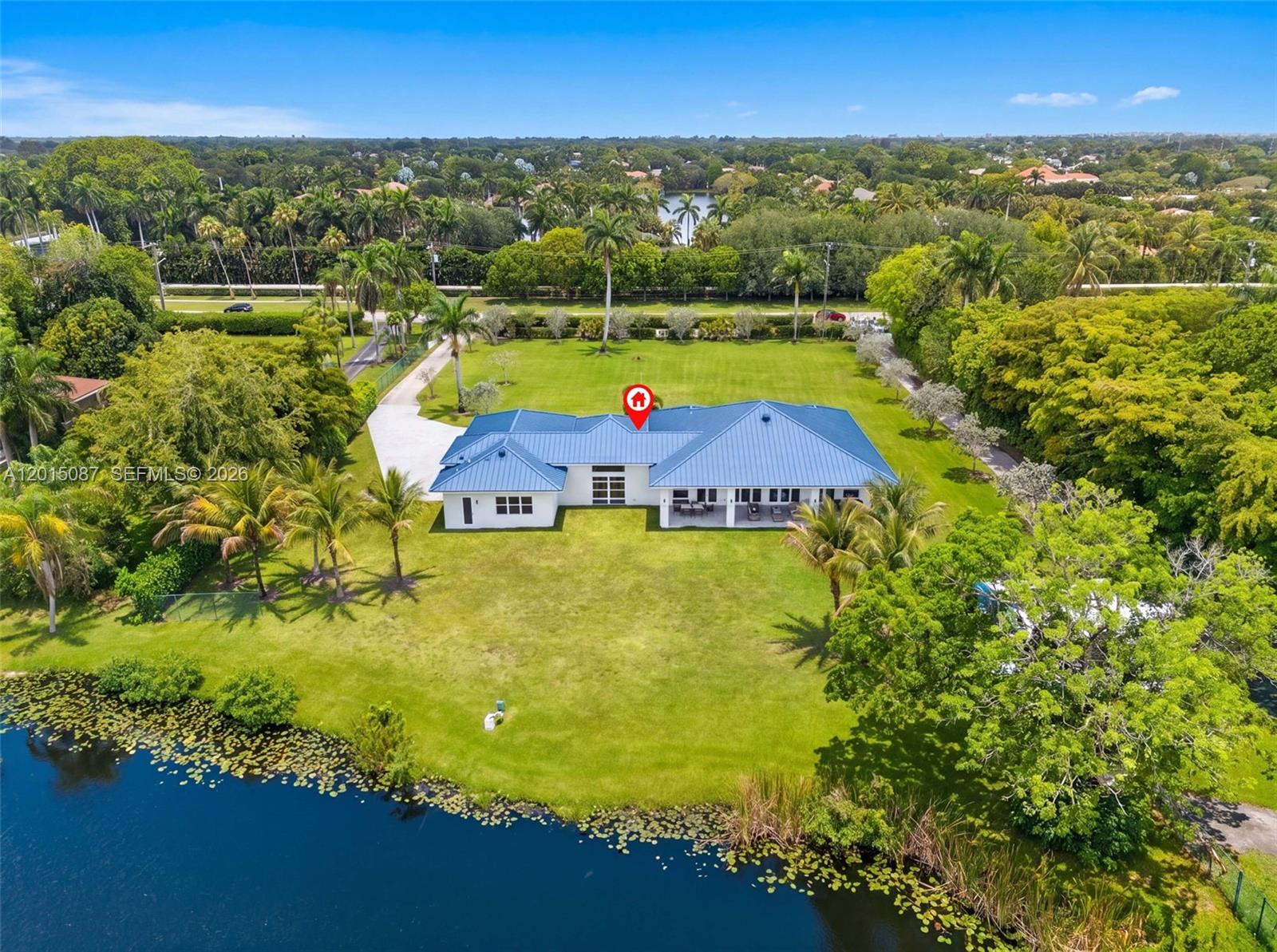 An aerial view of a white house with a blue metal roof beside a pond — 2400 SW 112th Ave, Davie FL 33325, DAVIE, FL