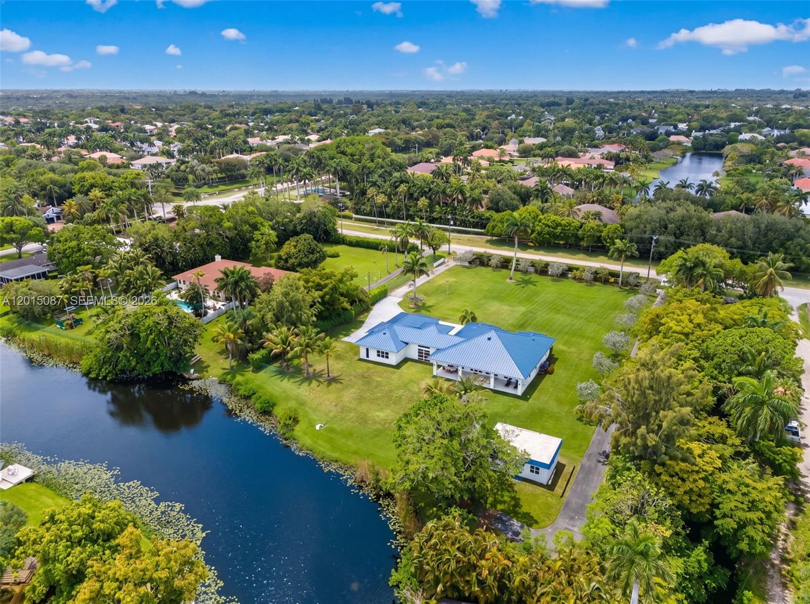 An aerial view shows a white house with a blue roof situated on a large lawn — 2400 SW 112th Ave, Davie FL 33325, DAVIE, FL