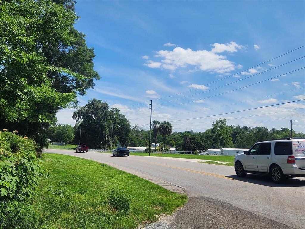 A view of a paved road with cars, trees, and a white fence under blue skies — TBD 97TH STREET ROAD, ANTHONY, FL