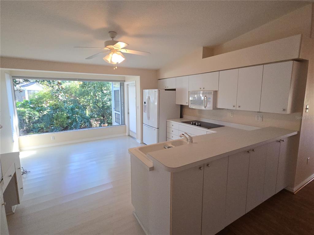 A kitchen with white cabinets, a breakfast bar, and a large window overlooking trees — 11519 HOLLY ANN DRIVE, NEW PORT RICHEY, FL