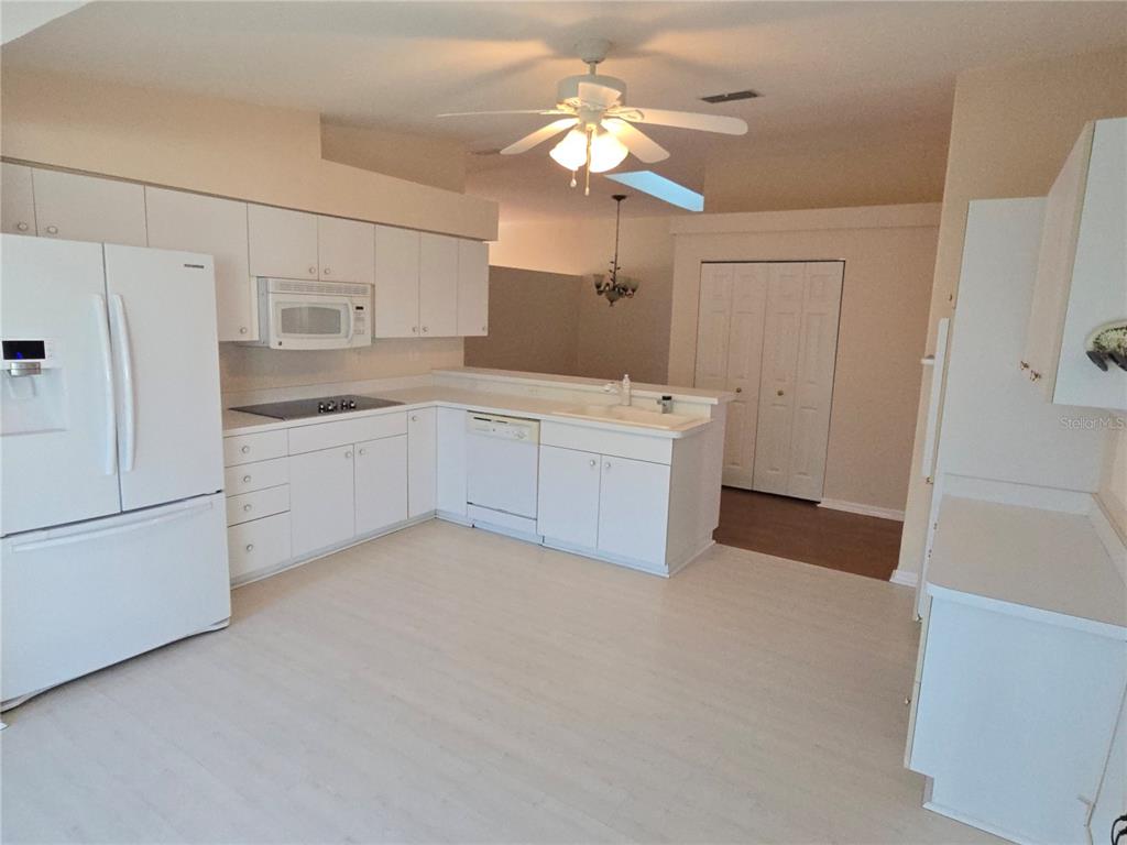 A kitchen features white cabinets, white appliances, a ceiling fan, and light-colored flooring — 11519 HOLLY ANN DRIVE, NEW PORT RICHEY, FL