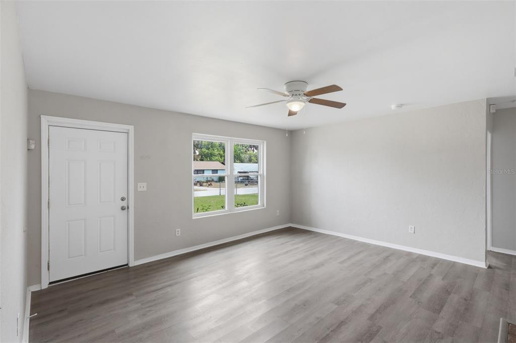 An empty room with light gray walls, wood-look flooring, a ceiling fan, and a door — 748 COLFAX DRIVE, DAYTONA BEACH, FL
