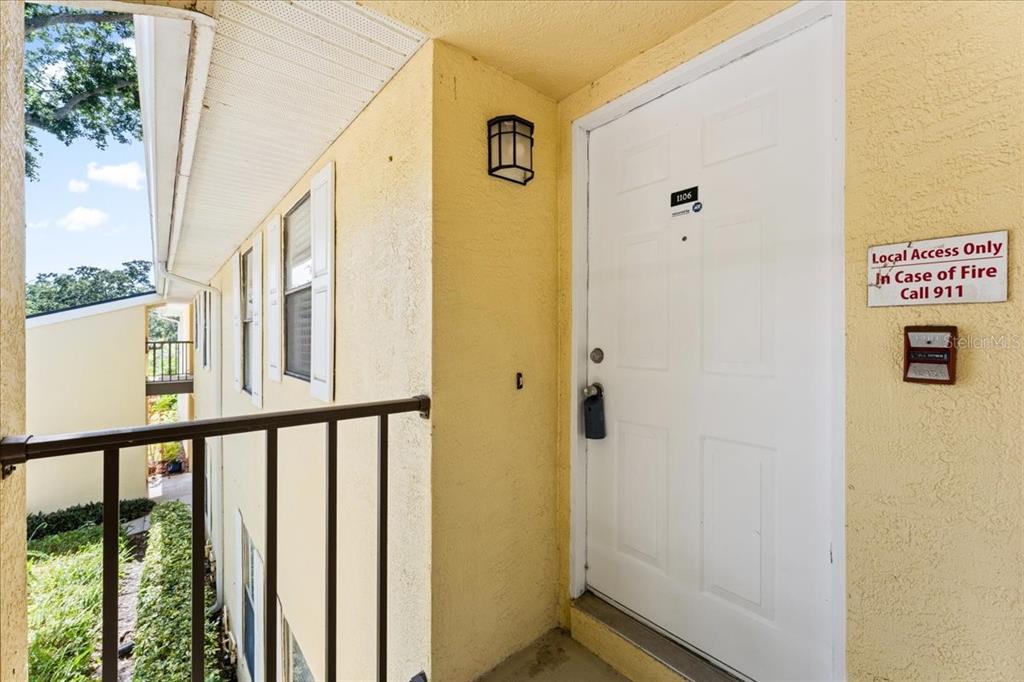 An exterior view of a yellow apartment building entrance with a white door — 3001 58TH AVENUE S UNIT 1106, ST PETERSBURG, FL