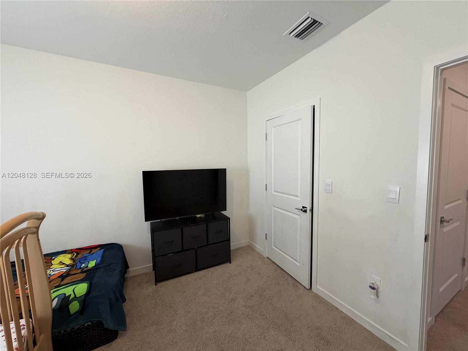 A bedroom features a television on a black dresser, a child's bed, and two doors — 159 NE 13th Ter, Homestead FL 33033, HOMESTEAD, FL