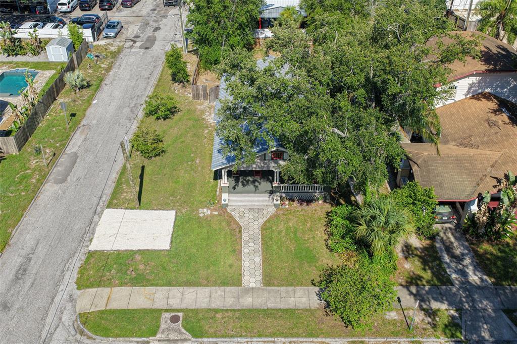 An aerial view shows a house with a metal roof, front porch, and paved walkway — 6002 N SUWANEE AVENUE, TAMPA, FL