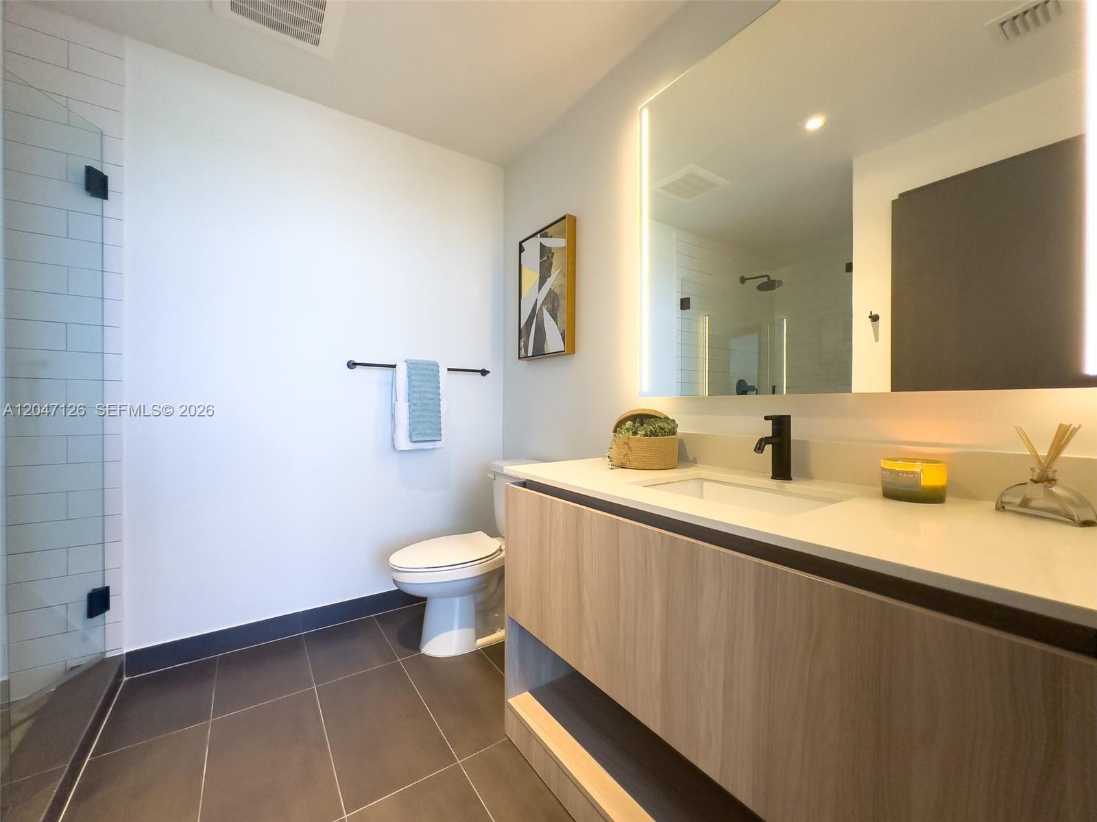 A modern bathroom features a floating wood vanity, a backlit mirror, and a glass shower — 398 NE 5th St # 4210, Miami FL 33132, MIAMI, FL