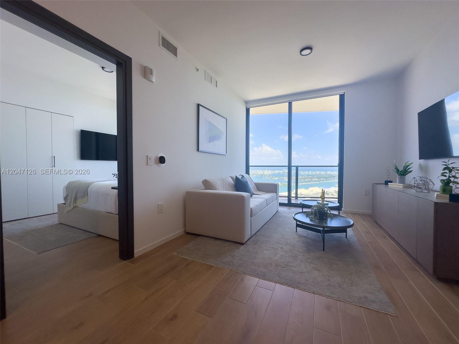 A living room with a sofa, coffee tables, and a view of the ocean — 398 NE 5th St # 4210, Miami FL 33132, MIAMI, FL