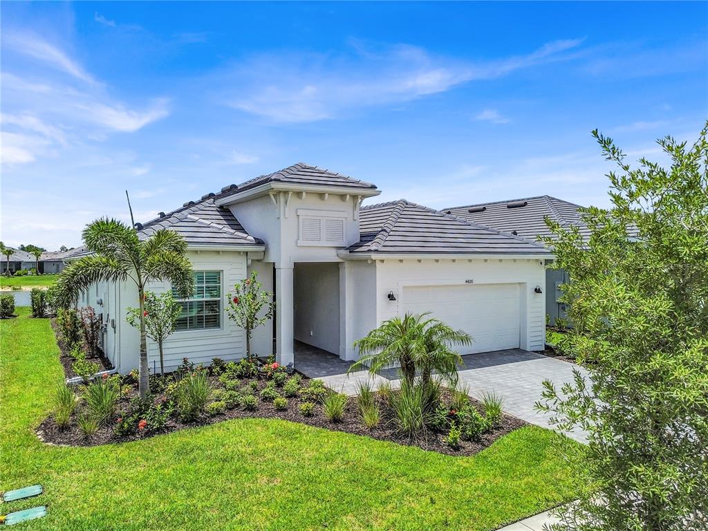 A single-story house with a white exterior, gray tile roof, and a two-car garage — 44281 HENDERSON WAY, PUNTA GORDA, FL