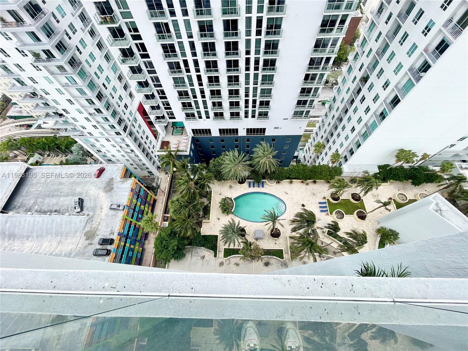 A high-angle view shows a swimming pool and palm trees between two tall apartment buildings — 253 NE 2nd St # 2506, Miami FL 33132, MIAMI, FL