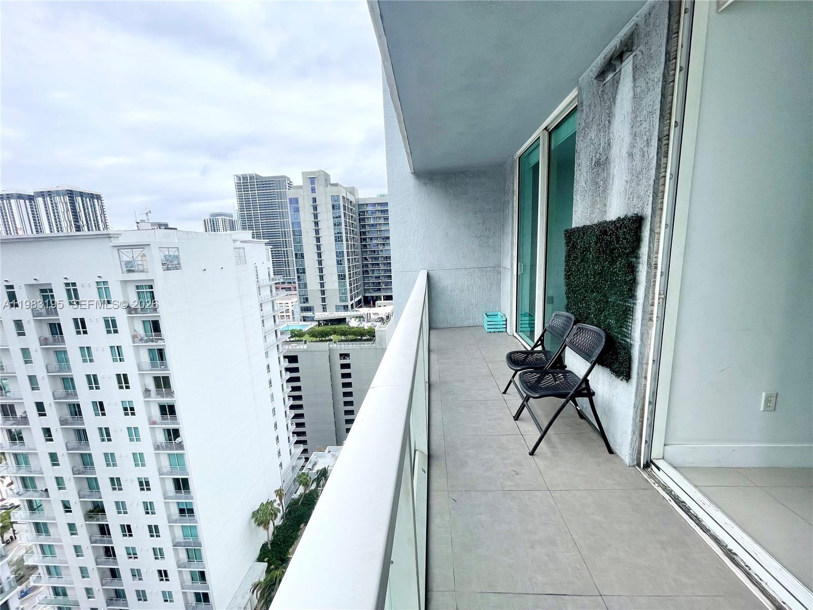 A balcony with two black folding chairs overlooks a city skyline with high-rise buildings — 253 NE 2nd St # 2506, Miami FL 33132, MIAMI, FL