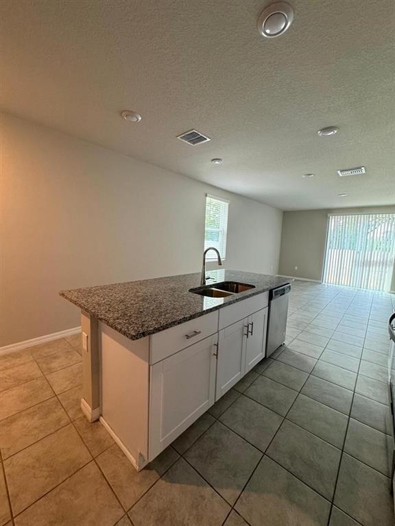 A kitchen island with a granite countertop and white cabinets sits on a tiled floor — 1868 CARNOSTIE ROAD, WINTER HAVEN, FL