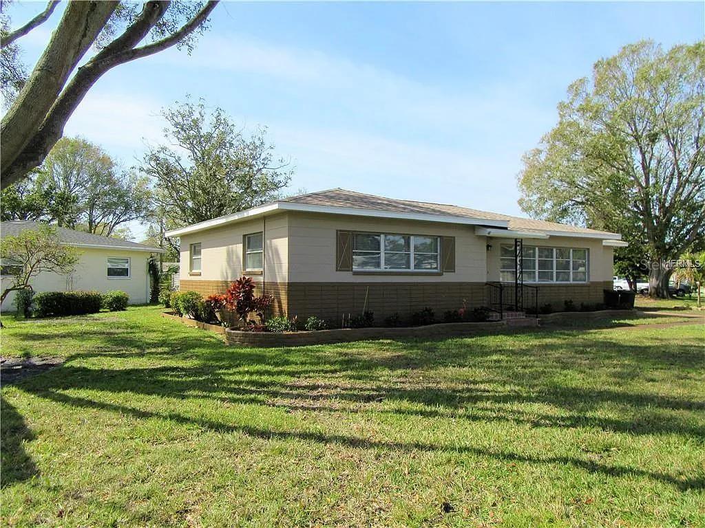 A single-story house with tan siding and a brick base sits on a grassy lot — 5800 21ST AVENUE S, GULFPORT, FL