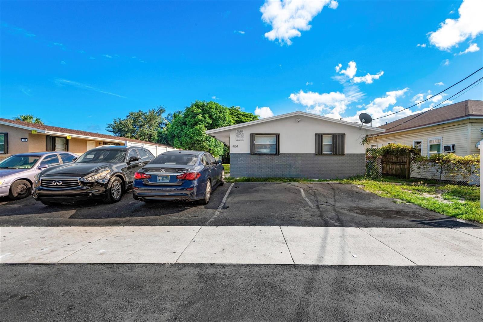 A single-story house with a gray brick base and two parked cars in the driveway — 404 NE 4th Street, Pompano Beach FL 33060, POMPANO BEACH, FL