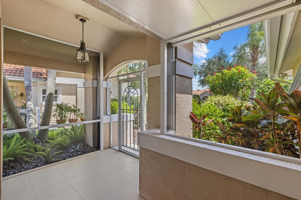 A screened-in patio with tile flooring, a hanging lantern, and views of lush landscaping — 4444 DEER TRAIL BOULEVARD, SARASOTA, FL
