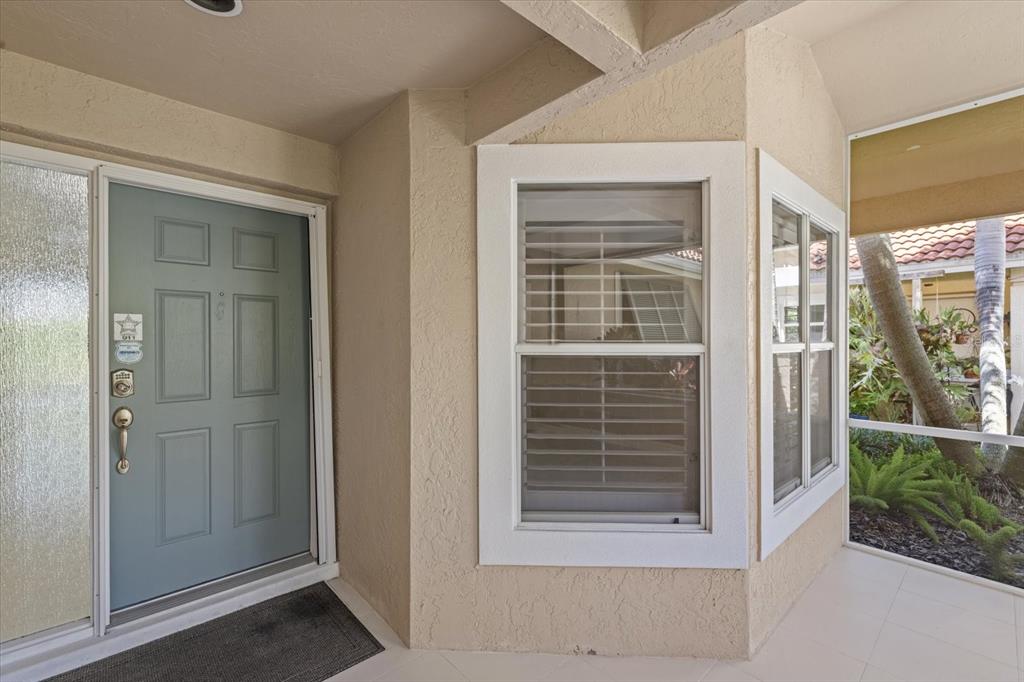 A light blue front door sits beside a bay window on a covered porch — 4444 DEER TRAIL BOULEVARD, SARASOTA, FL