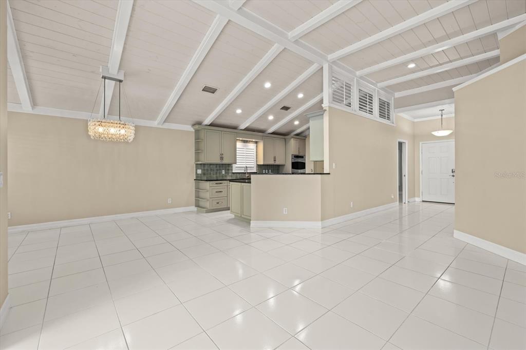 An open-concept living area features white tile floors, a vaulted ceiling, and a kitchen — 4444 DEER TRAIL BOULEVARD, SARASOTA, FL
