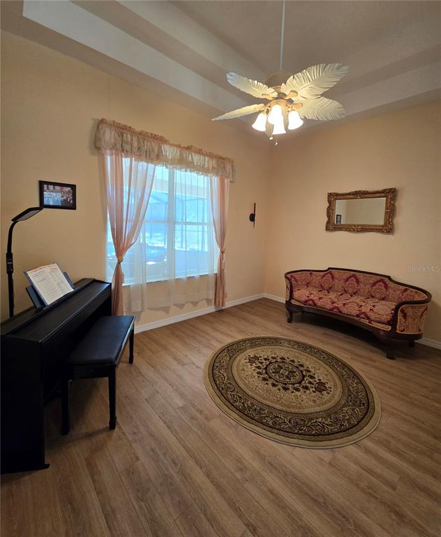 A room features light-colored walls, wood-look flooring, a piano, a patterned sofa, and a ceiling fan — 25344 CROOM ROAD, BROOKSVILLE, FL
