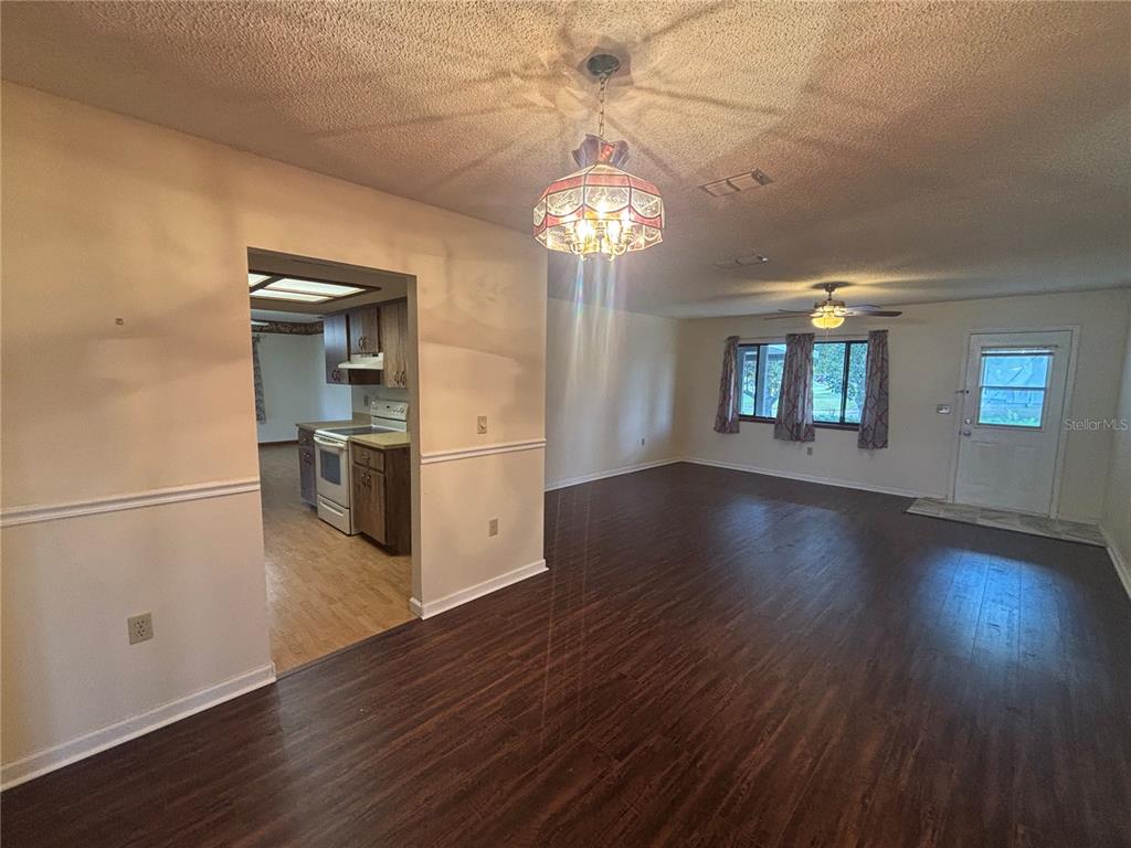 A living room with dark wood floors leads into a kitchen with light wood cabinets — 10211 SW 93RD COURT, OCALA, FL
