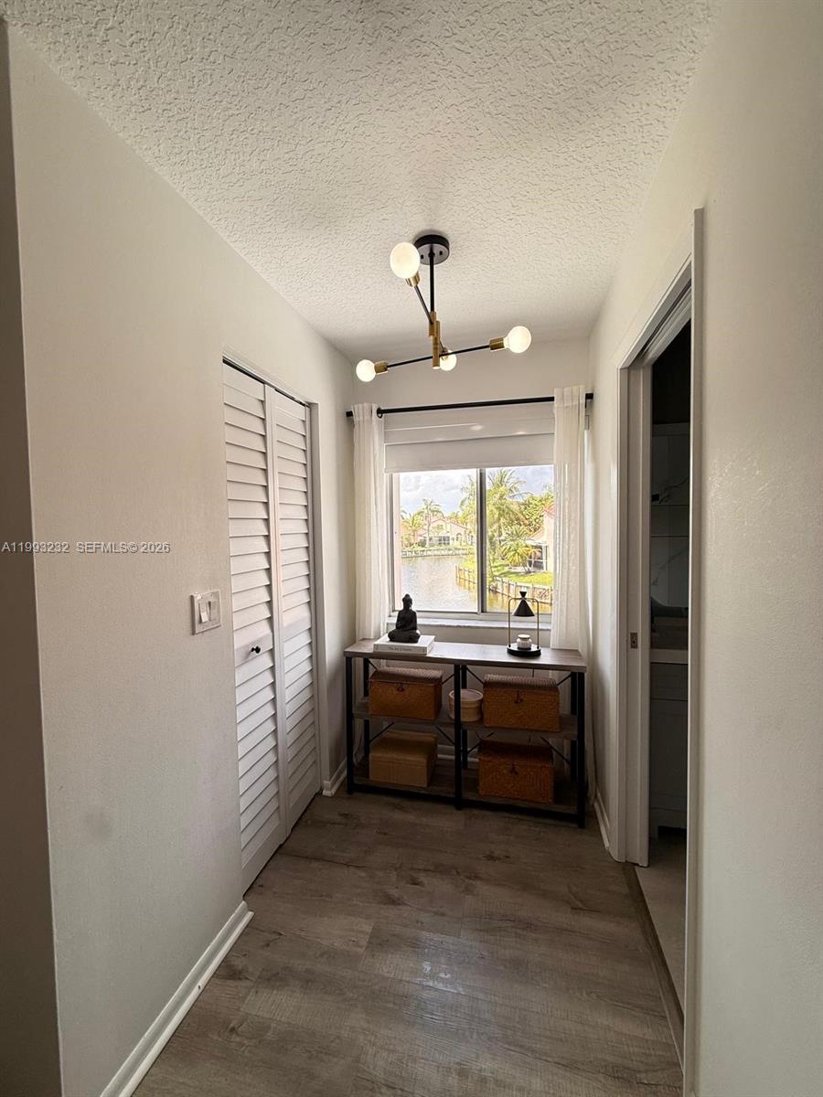 A hallway features wood-look flooring, a louvered closet, a console table, and a window view — 1054 SE 6th Ct, Dania Beach FL 33004, DANIA BEACH, FL