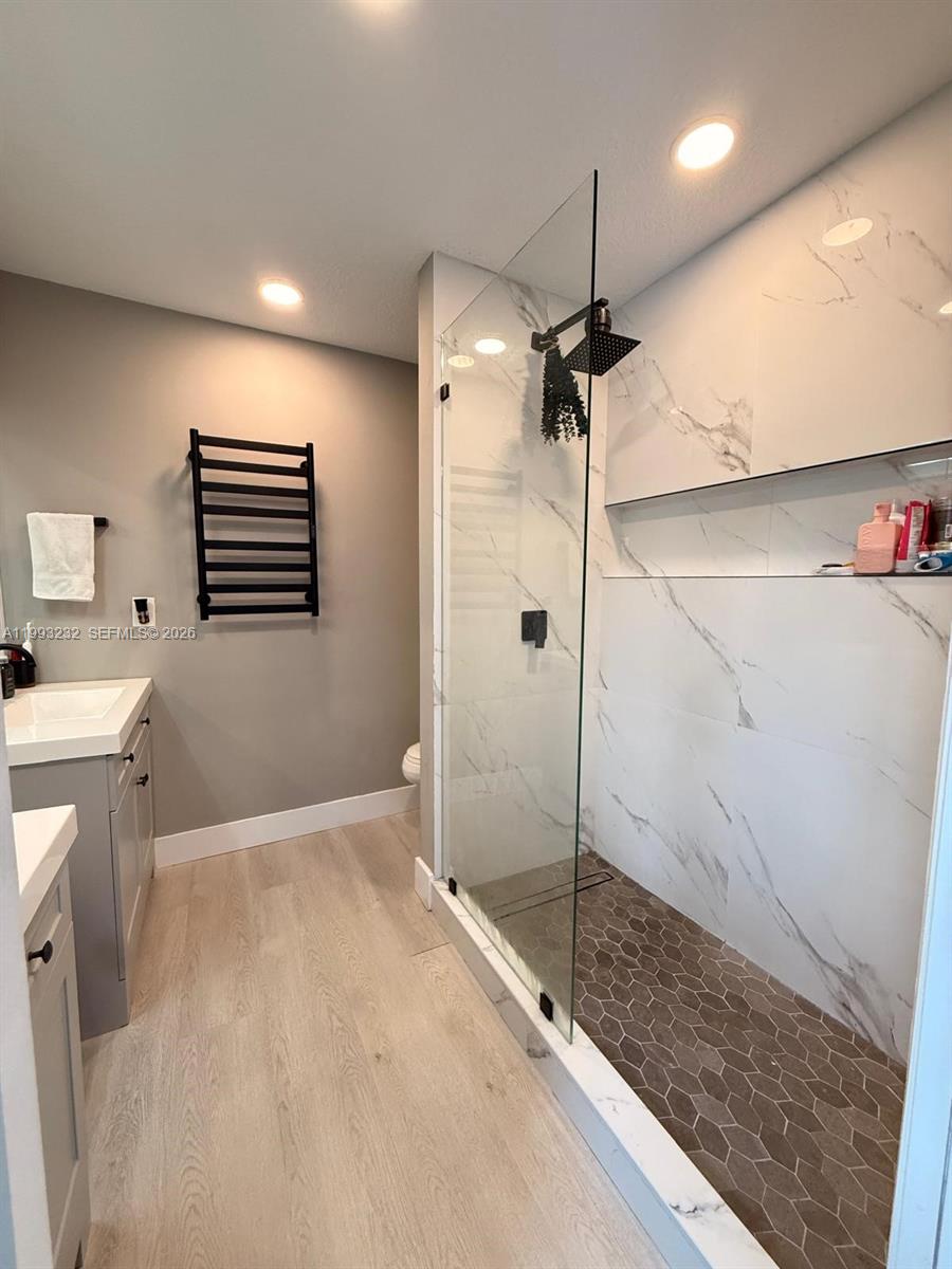 A modern bathroom features a glass-enclosed walk-in shower with marble tile and hexagonal flooring — 1054 SE 6th Ct, Dania Beach FL 33004, DANIA BEACH, FL