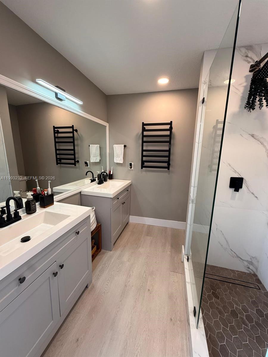 A modern bathroom features dual gray vanities, a glass-enclosed shower, and black hardware — 1054 SE 6th Ct, Dania Beach FL 33004, DANIA BEACH, FL